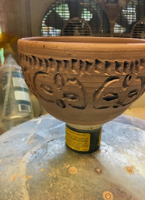 hand carved bowl sitting on  a jar made by  local potter & Realtor Ron Zemetres